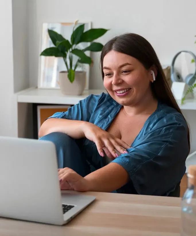 Pessoa em sessão de terapia online em casa, sorrindo diante do notebook