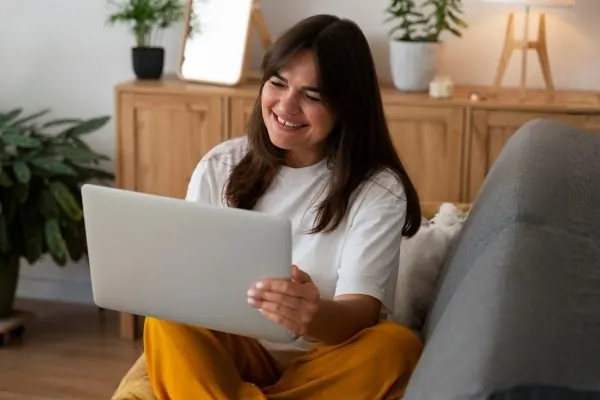 Mulher em sessão de terapia online em casa, sorrindo diante do notebook